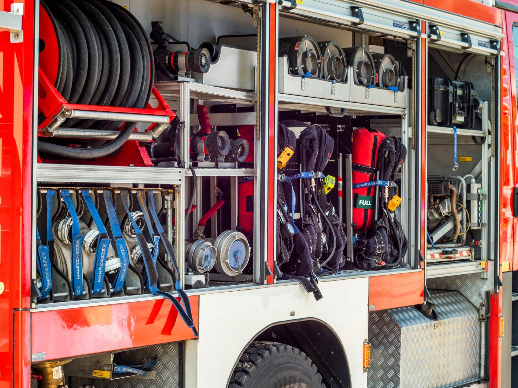 Close-up view of fire truck equipment storage showcasing hoses, tools, and gear.