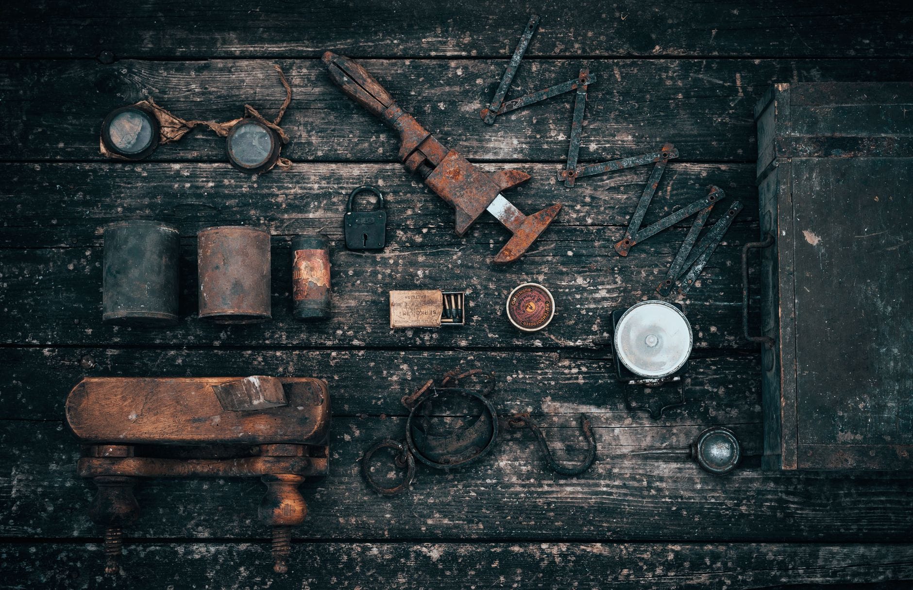 Top view of various old carpentry tools and tin cans arranged on shabby wooden table in garage